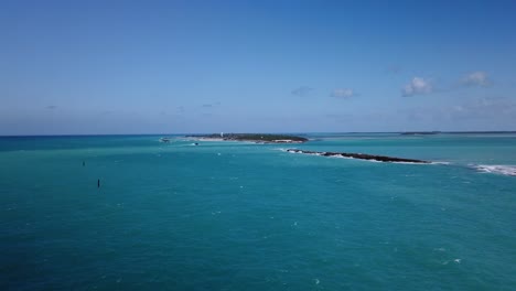 windy summer morning in the caribbean looking out on the turquoise water of the sea and small islands in the distance with waves crashing against the shoreline