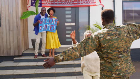 multi-generation family with parents and wife welcoming army soldier home on leave with banner