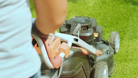 lawn mower cutting the grass. gardening activity. cutting grass with petrol driven lawn mower in sunny garden. gardener working with mower machine in the garden. lawn mower cutting green grass