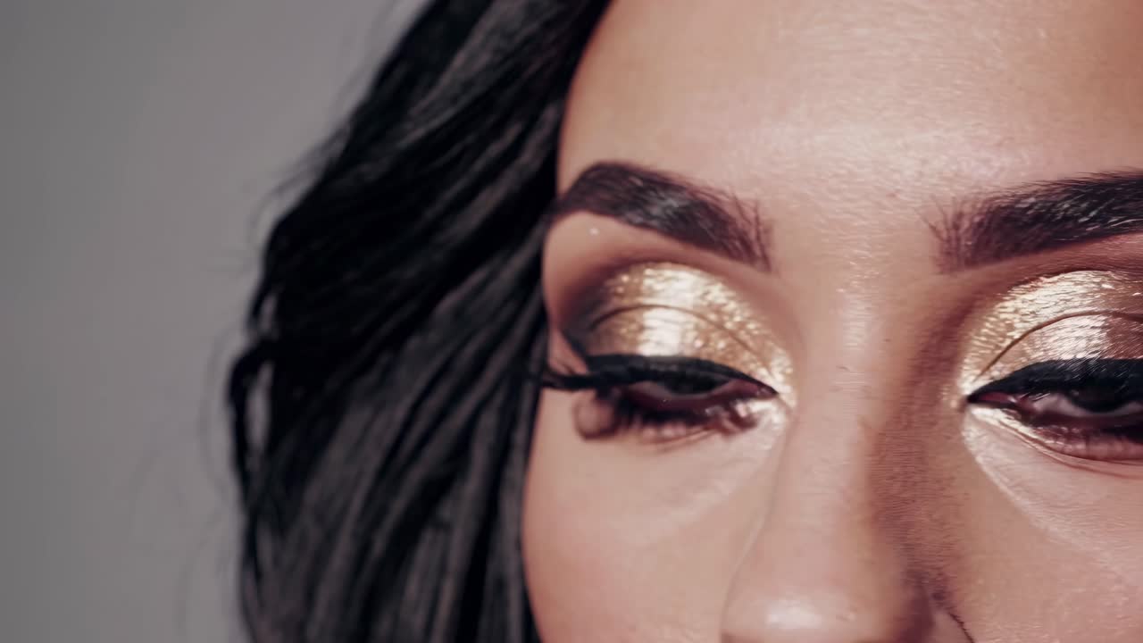 Close-up video of glamorous eye makeup with gold shimmer and bold eyeliner