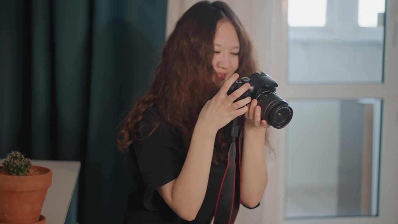 カメラを下ろし、背面ディスプレイで画像を確認しながら指で操作を調整する若い女性。撮影後のリラックスした満足感と集中して取り組んでいる様子がうかがえる。