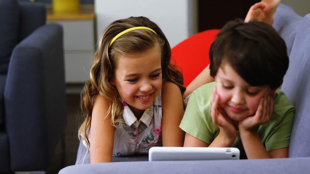 hermanos usando tableta digital en la sala de estar