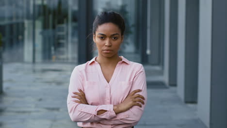 woman with arms crossed in front of an office building