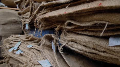 sacos de café de yute natural usados y gastados con escritura roja apilados en un almacén de producción de café
