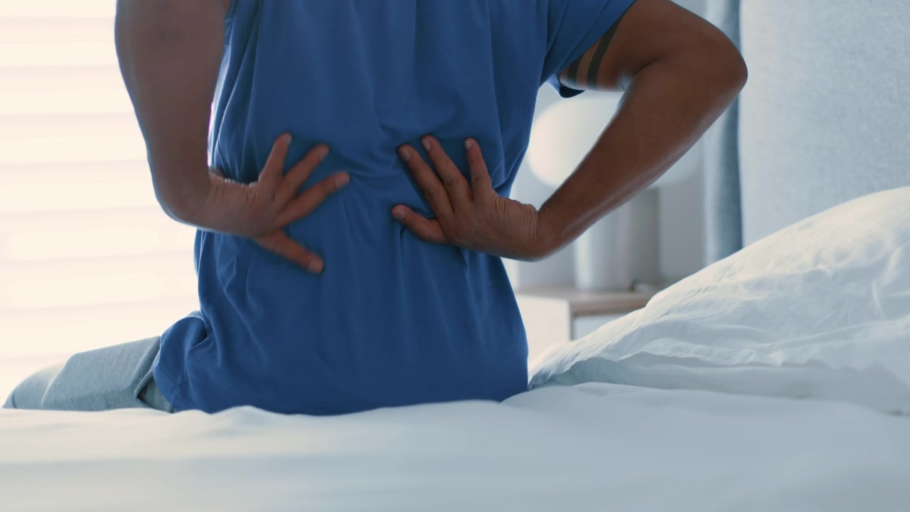 Person Sitting on Bed Suffering From Back Pain