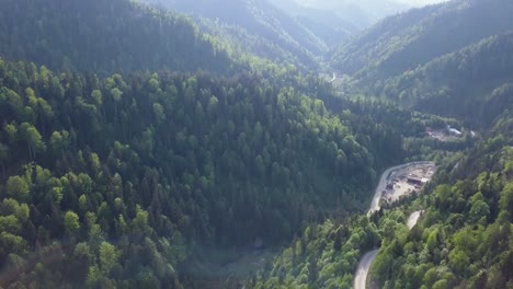 Aerial-Downwards-Panning-shot-of-valley-with-road-in-the-foreground-and-reservoir