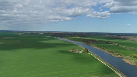 high aerial shot over a rural gravel road with green canola fields and wheat fields along rural landscape at daytime