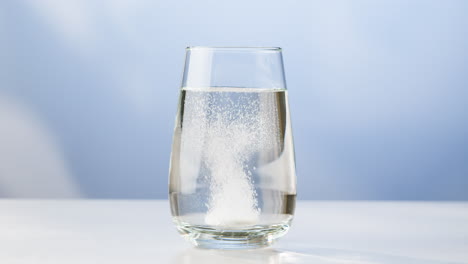 dissolving a pill in a glass of water