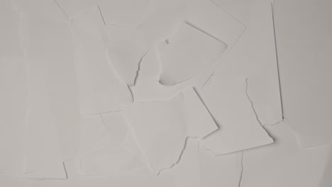 stop motion sequence of torn pieces of paper moving to uncover green screen background below 1