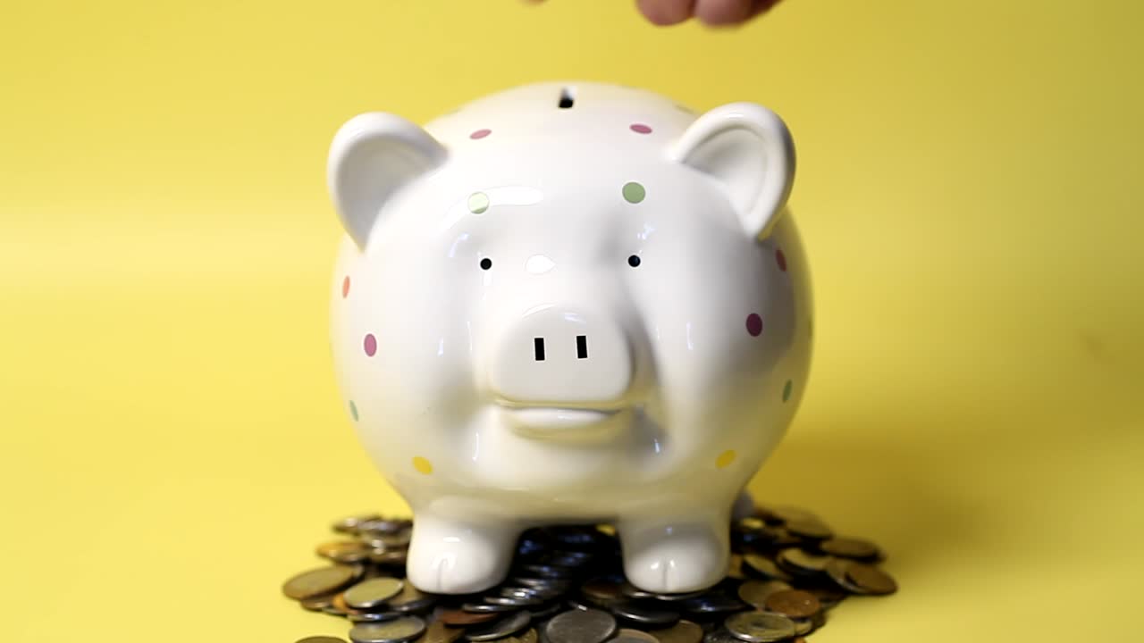 Hand putting coins in Piggy Bank.4K