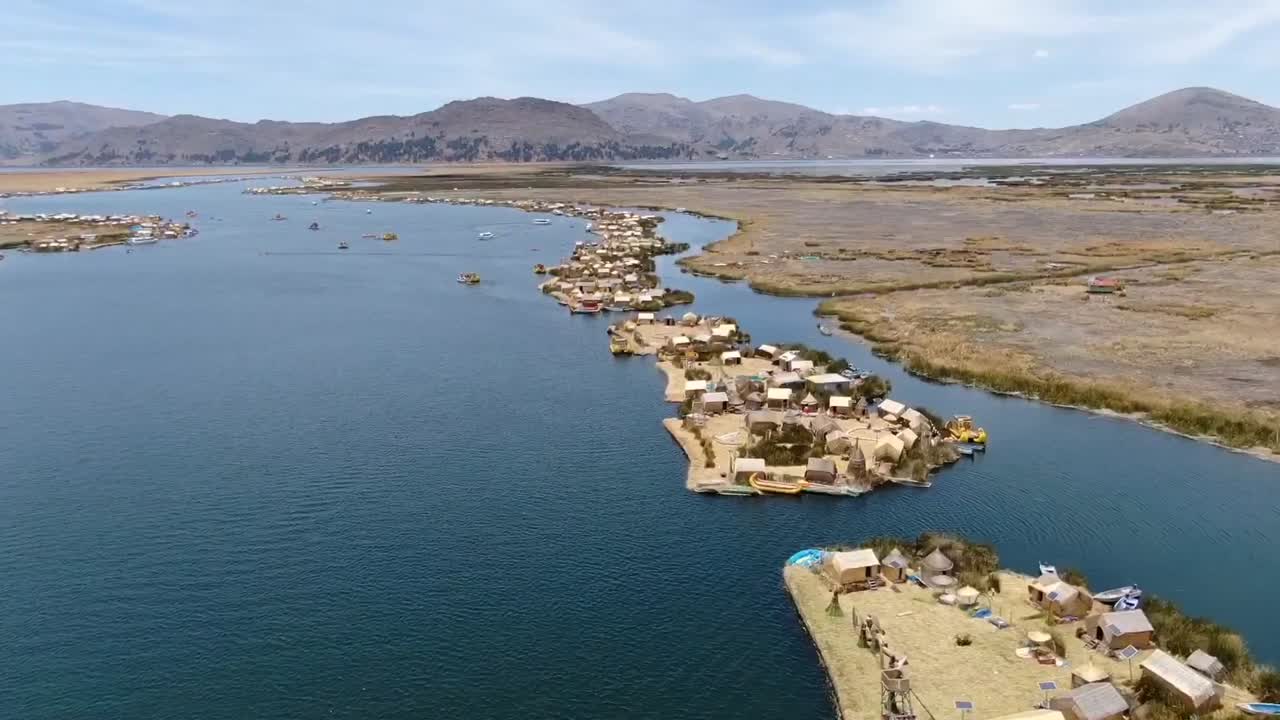 vista aérea de drones en perú volando sobre asentamientos huros en pequeñas islas con pequeños barcos y casas artificiales en el lago titikaka en puno en un día soleado