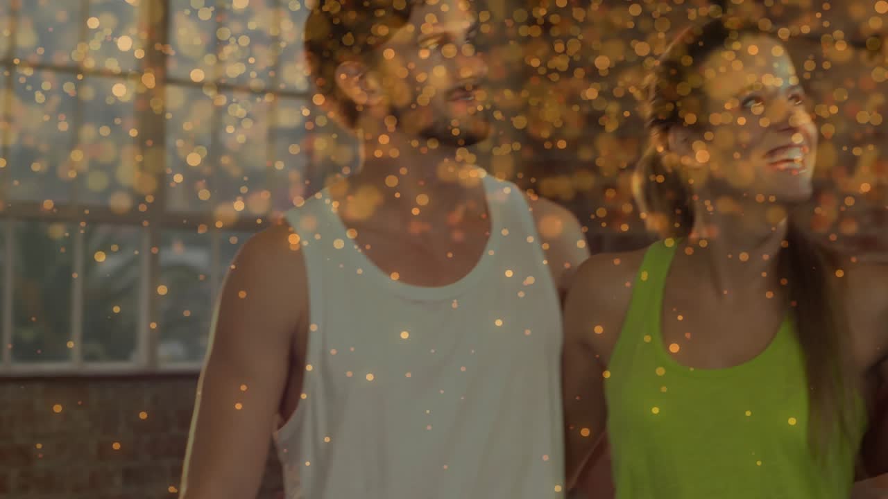 Three adults smiling and laughing to off-camera cue in loft, gold overlay celebrating fitness bond
