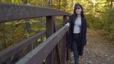 A-petite,-slender-white-girl,-with-bangs,-leaning-against-a-rusted-metallic-railing