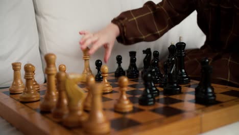 close up of hands of small girl play with wooden figurines of chess, smart kid