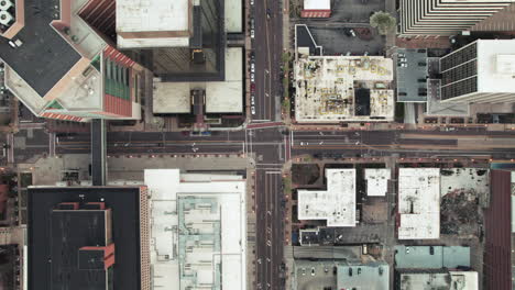 aerial zoom out directly above downtown intersection with sparse city traffic