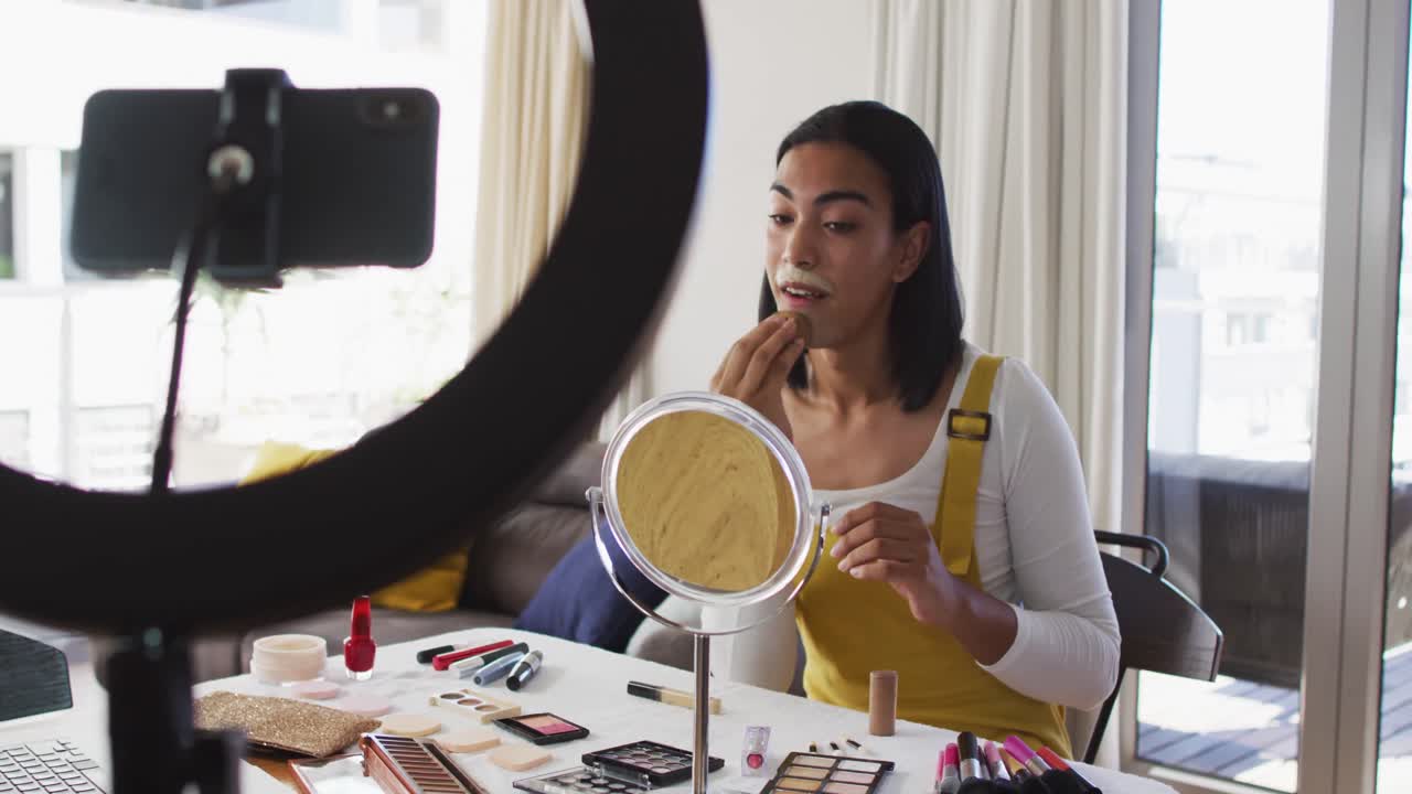 vlogger de género fluido de raza mixta grabando un vlog de maquillaje en casa