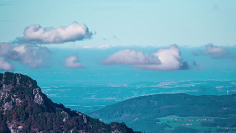 Clouds-billow-growing-and-fading-in-sky-above-expansive-forested-mountains