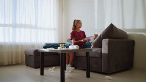 caring sister hands thermometer to feverish brother to check his temperature, tissue littered around with natural light casting shadows on wall creating an intimate, homey atmosphere