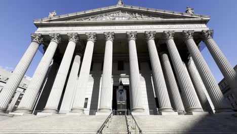 An-imposing-upward-view-of-the-New-York-County-Courthouse,-highlighting-its-grand-columns-and-monumental-steps,-symbolizing-justice-and-the-rule-of-law-in-the-heart-of-Manhattan