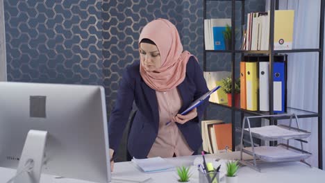 muslim business woman in hijab takes and analyzes notes in office.