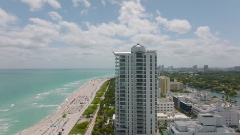 Row-of-multistorey-residential-buildings-along-sea-coast-in-tropical-destination.-Aerial-view-of-sandy-beach.-Miami,-USA