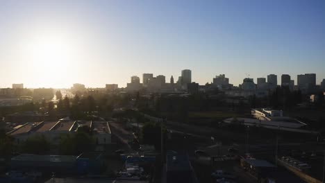 Drone-flying-over-the-Clinton-district,-towards-the-sunlit-downtown-Oakland-in-California,-USA