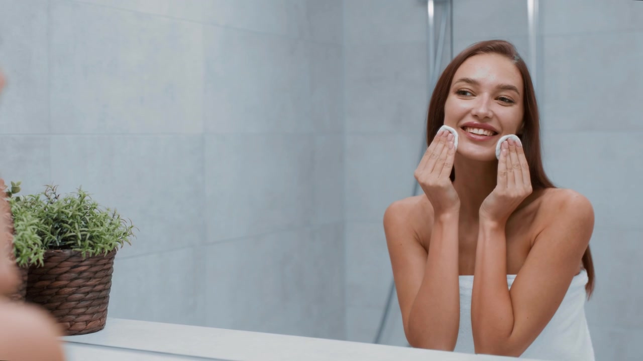 Young Woman Cleaning Her Face with Cotton Pads in Bathroom