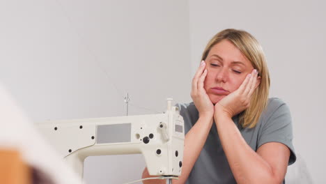 woman resting cheeks on hands in front of textile machine, engaged in lively discussion with colleague, showing thoughtful expression, focused interest, comfortable posture, relaxed environment