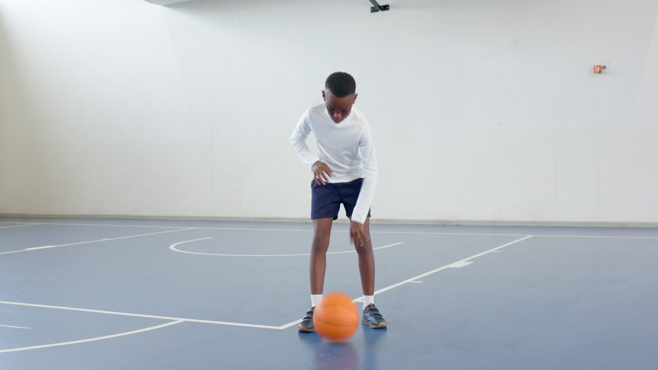 Practicing basketball dribbling, african american boy focused and determined on court, copy space