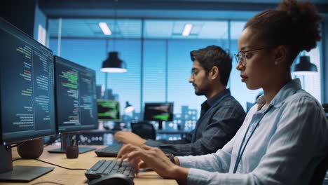 two developers collaborating in a modern office space, engaged in programming and problem solving with coding on dual monitors, demonstrating teamwork and technology skills