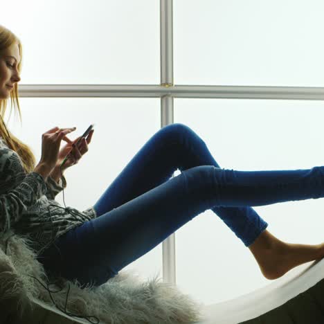 woman sitting in round window listening to music