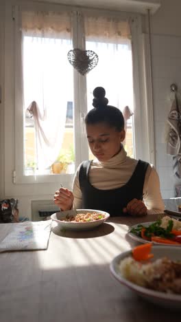 chica comiendo una comida en una cocina soleada