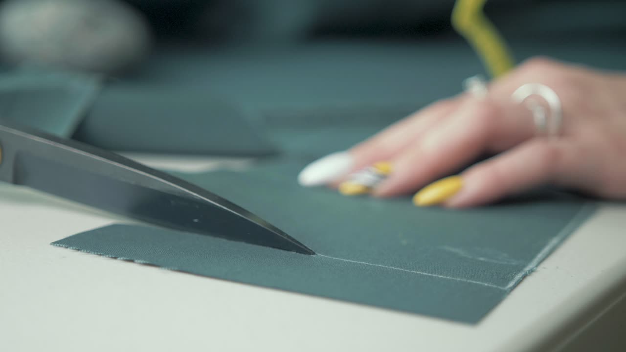 sastre cortando tela verde con tijeras