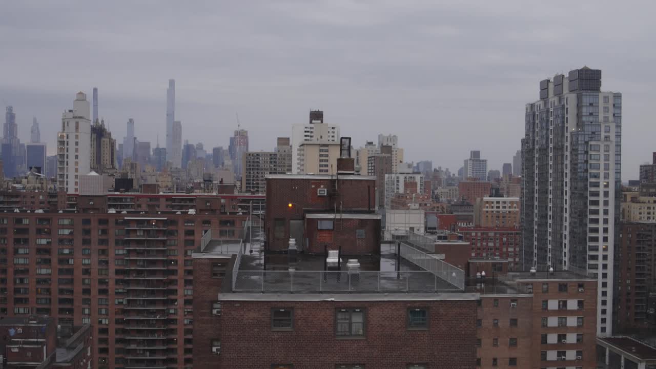 뉴욕 시의 지붕에서 촬영 된 트 다운은 스카이 라인에서 시작하여 비가 오는 날 인근의 벽돌 주거 건물의 높이를 보여주기 위해 아래로 기울어집니다.