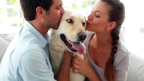 pareja riendo acariciando a su perro labrador en el sofá