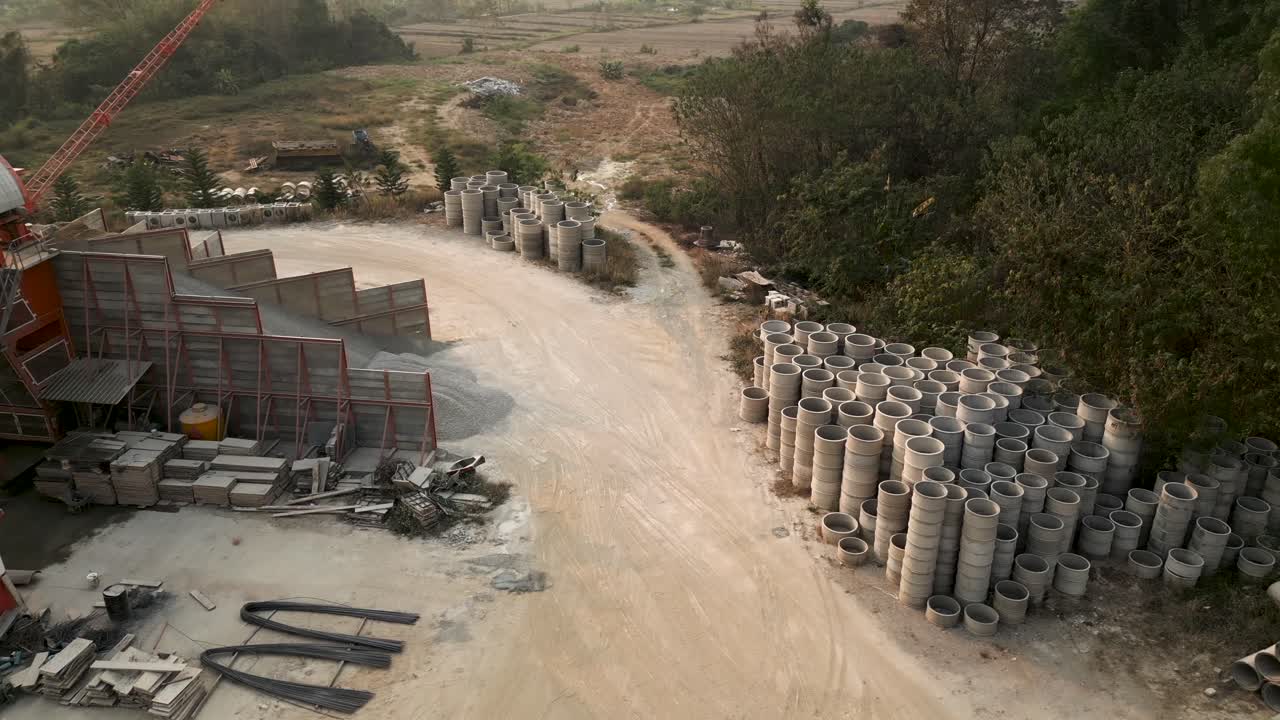 Aerial view of a construction material yard with concrete pipes and gravel storage