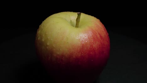 inclinación hacia arriba de manzana roja y amarilla cubierta de rocío aislada sobre fondo negro, primer plano