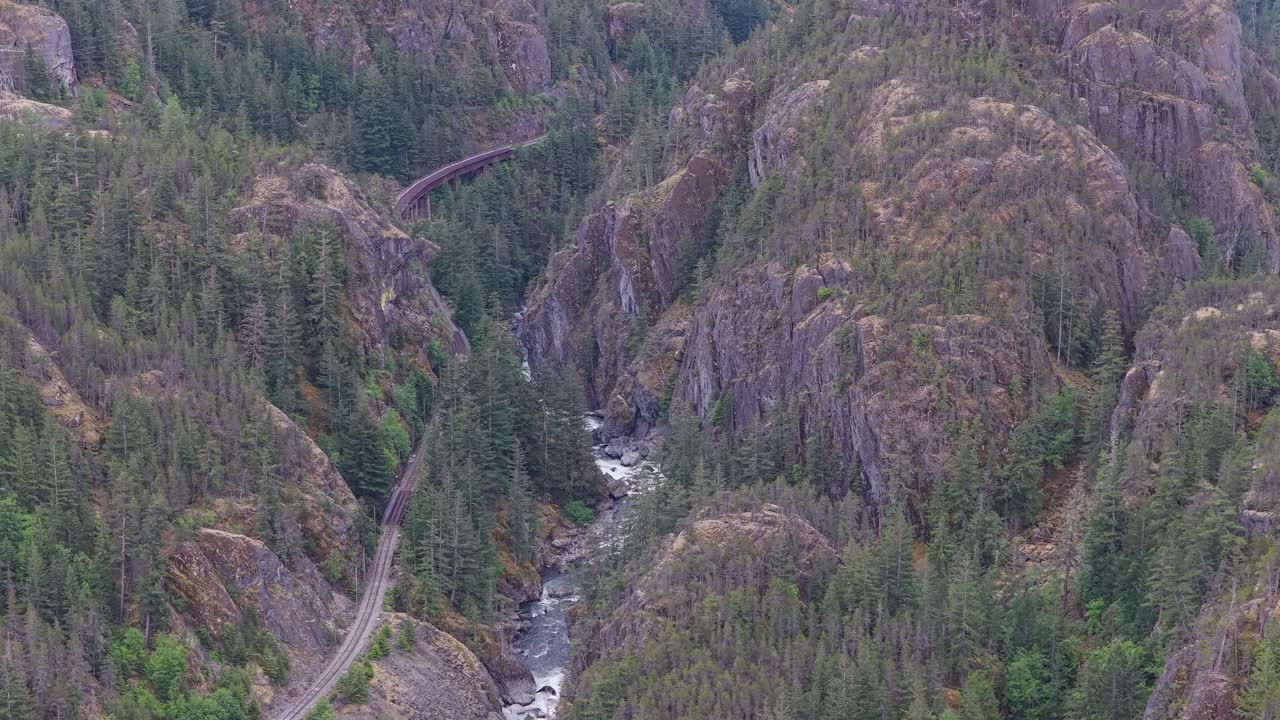 Train Tracks and River Winding Through Lush Green Forest Valley in BC