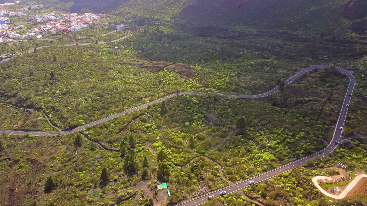 camino sinuoso en la isla de tenerife que conduce a un pequeño pueblo, vista aérea