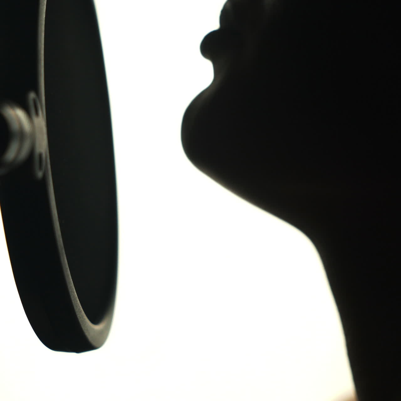 Young sexy profile of a woman with a beautiful face and lips. Girl singing to the microphone in a studio. Black and white Square video