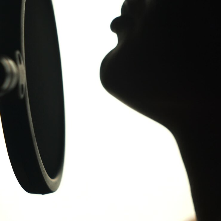 Young sexy profile of a woman with a beautiful face and lips. Girl singing to the microphone in a studio. Black and white Square video