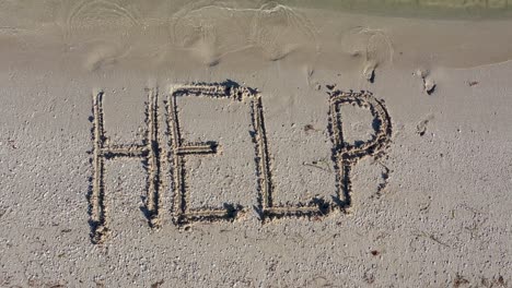 static shot of help written in the sand