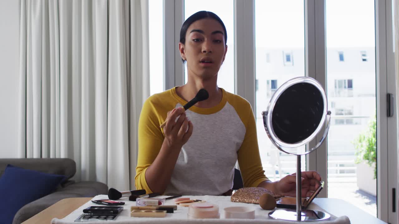 vlogger de género fluido de raza mixta grabando un vlog de maquillaje en casa