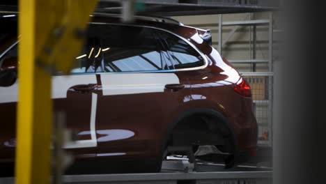 suv marrón siendo ensamblado en una cinta transportadora industrial en una fábrica de automóviles, primer plano borroso