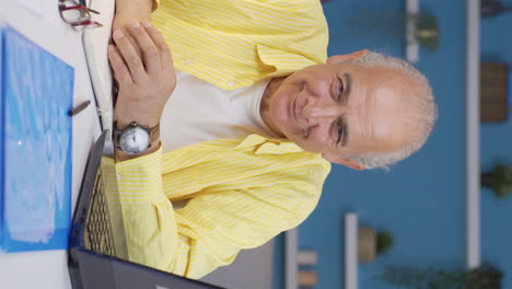 vertical video of home office worker old man nods to the camera.