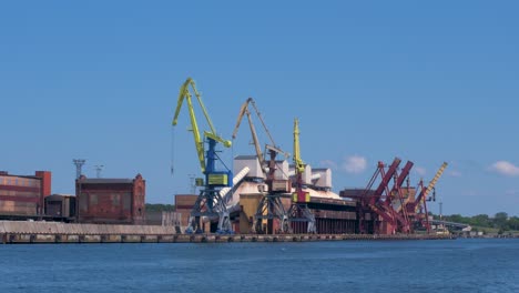 grúas portuarias y almacenes portuarios en un día soleado y tranquilo de verano en el puerto de ventspils, amplio plano desde la distancia