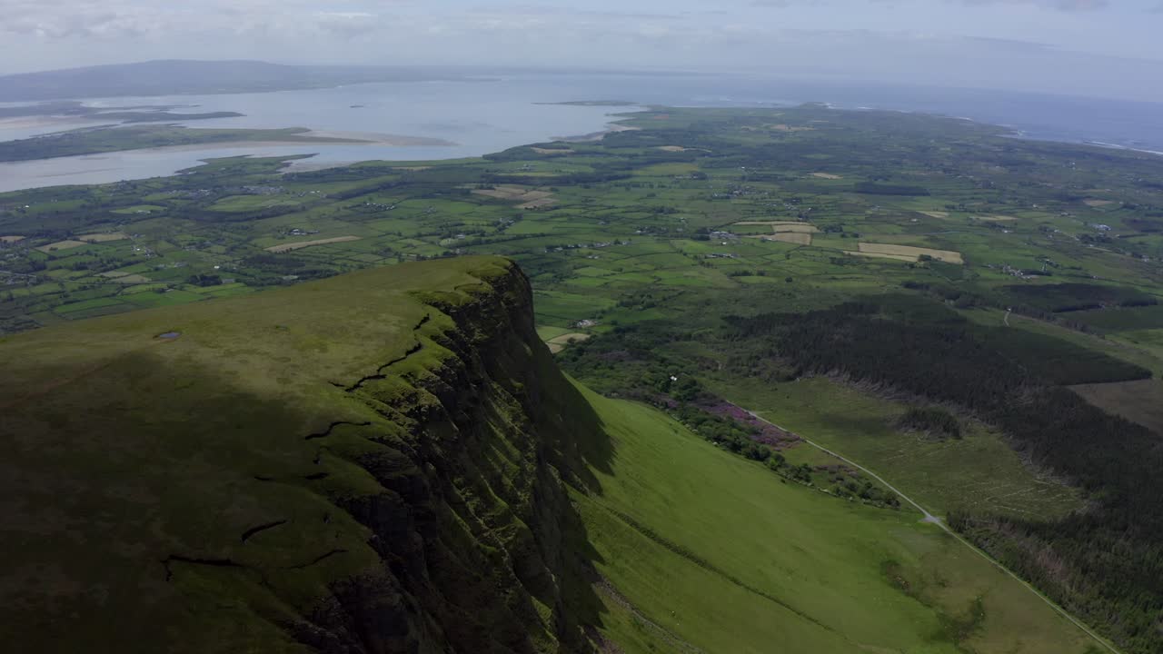 Benbulbin Mountain Sligo, Ireland, June 2021. Drone slowly tracks off the mountain top as shadows shroud the slopes revealing the southern face with views of Sligo Bay in the distance.