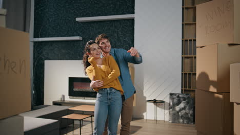 couple looking new home standing living room hugging. family discussing interior