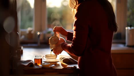 woman pouring tea in a warm kitchen