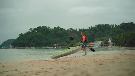 tourist getting ready to ride kayak on the beach in a hot summer day in el nido palawan - medium shot